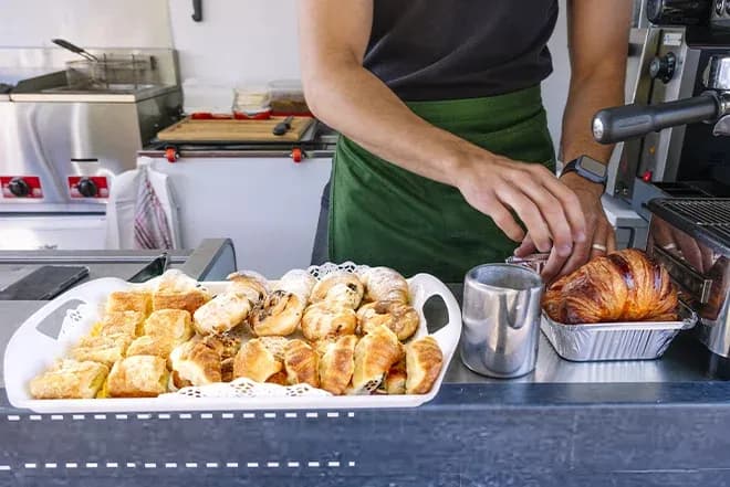 Vente de viennoiseries dans un camion avec des pâtisseries sur un plateau et une personne au travail