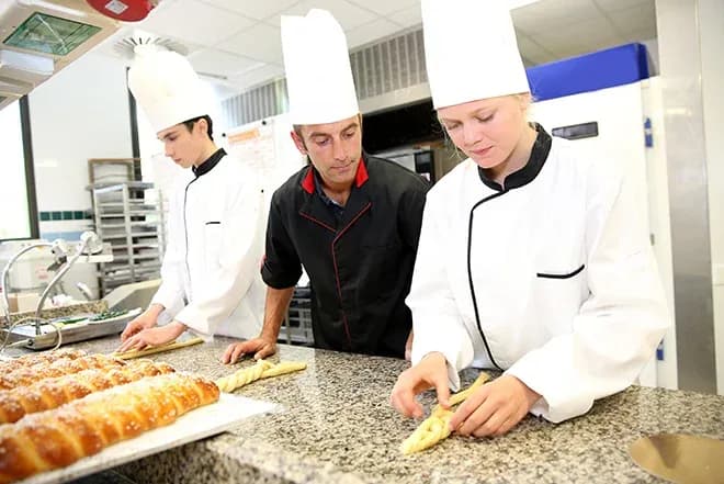 étudiants en boulangerie façonnant des tresses de pâte sous la supervision d'un chef