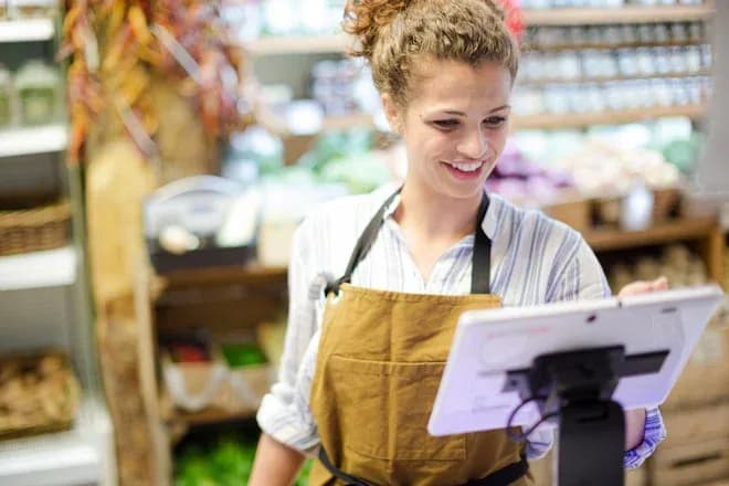 femme souriante utilisant une tablette dans un magasin de produits frais