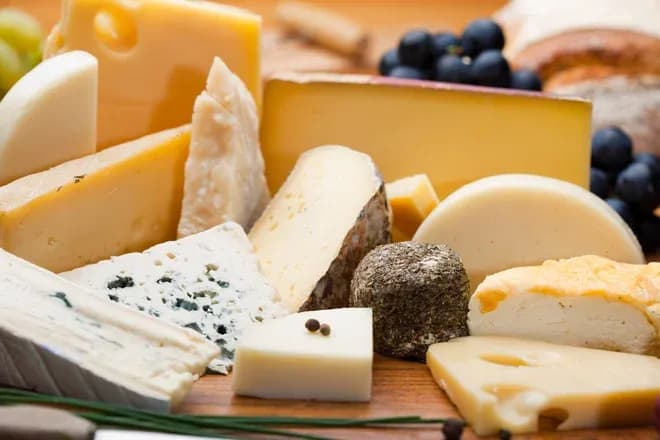 assortiment de fromages variés sur une planche en bois avec des raisins et du pain