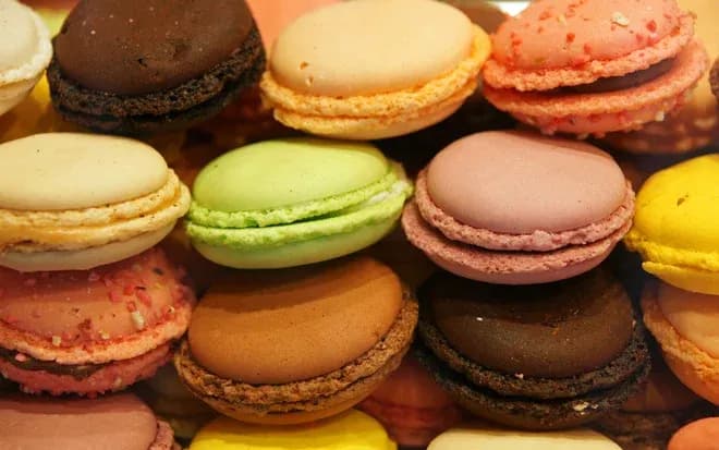 macarons colorés empilés sur un plateau en vitrine de pâtisserie