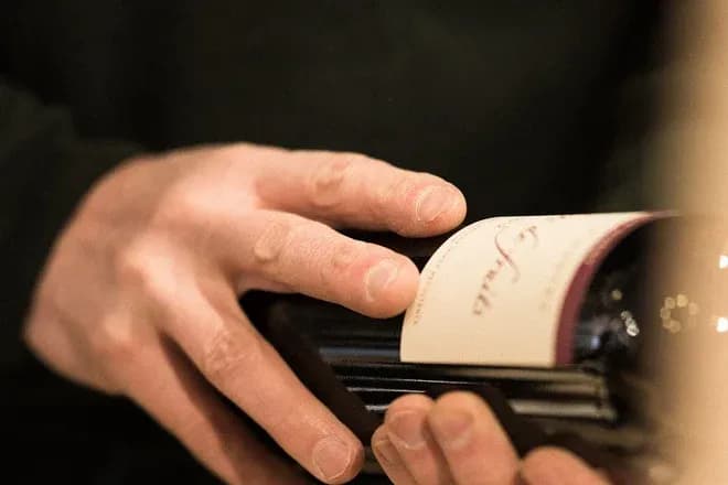 mains examinant l'étiquette d'une bouteille de vin