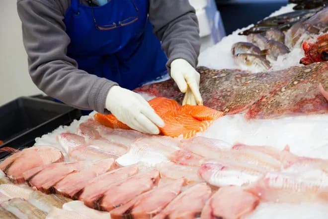 personne en train de préparer des filets de poisson sur un étal de marché