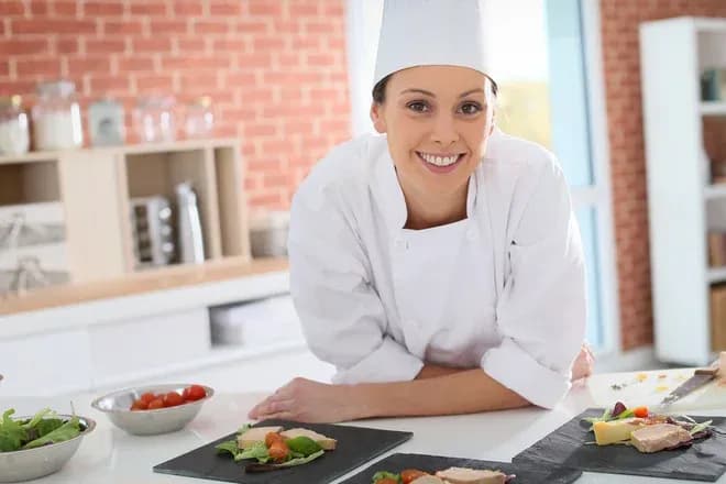 chef souriant devant des plats préparés sur une table de cuisine moderne