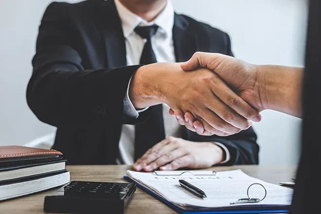 poignée de main lors de la signature d'un contrat sur un bureau avec documents