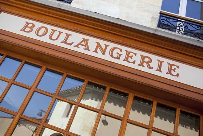 devanture d'une boulangerie avec une enseigne en bois et des fenêtres vitrées