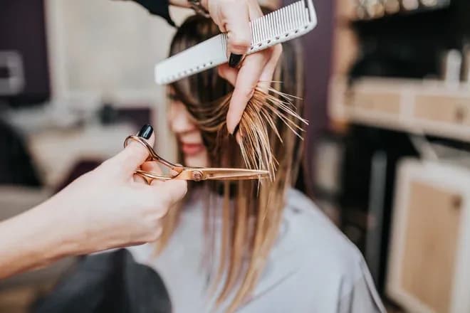 coiffeur coupe de cheveux avec des ciseaux et un peigne sur une cliente en salon
