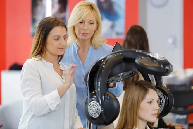 deux coiffeuses ajustent un casque de séchage sur une cliente