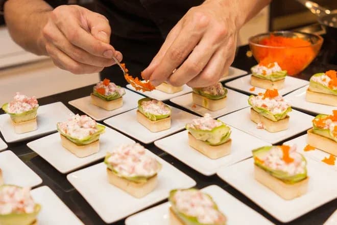 mains dressant des bouchées apéritives garnies d'œufs de poisson