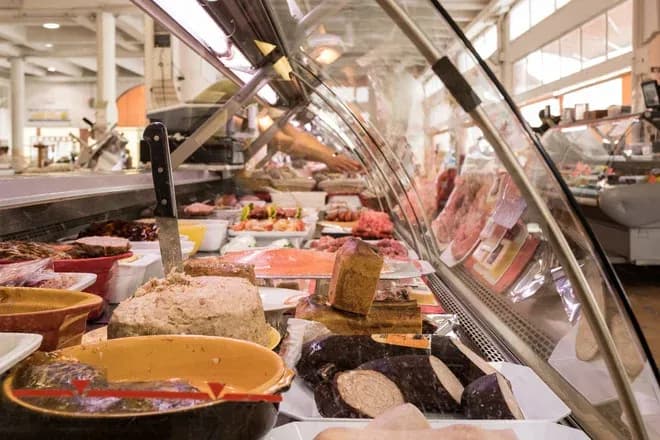 comptoir de charcuterie et terrines sous vitrine dans un marché animé