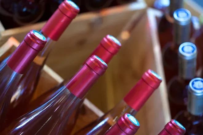 bouteilles de vin rosé avec capsules rouges dans des caisses en bois