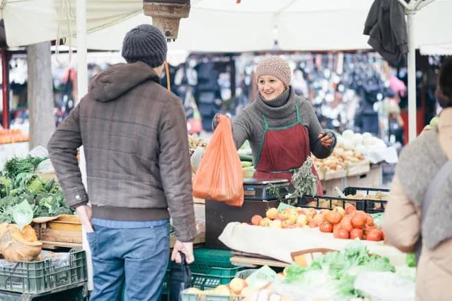 vendeuse souriante remet un sac de légumes à un client au marché