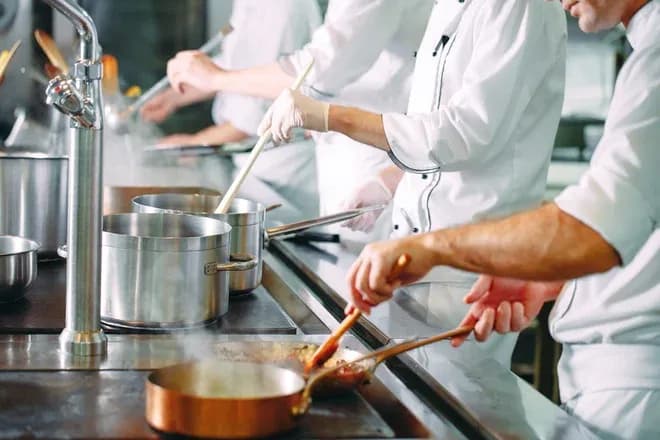 chefs en cuisine professionnelle remuant des sauces et plats dans des casseroles