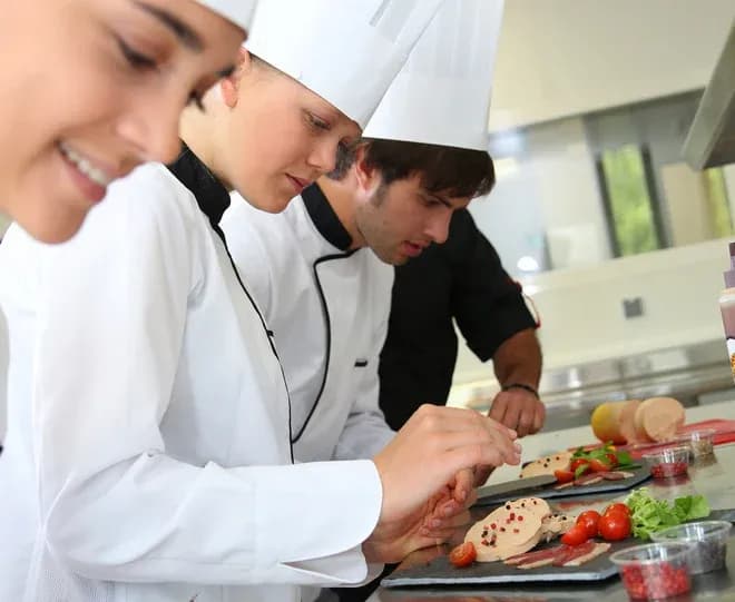 cuisiniers en train de préparer des plats avec des légumes et de la viande dans une cuisine moderne