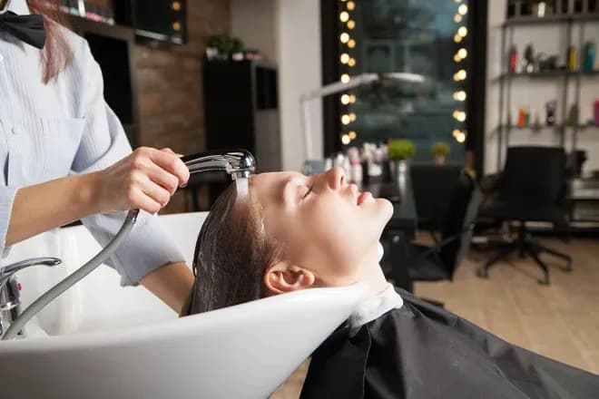 femme se faisant rincer les cheveux au bac par une coiffeuse