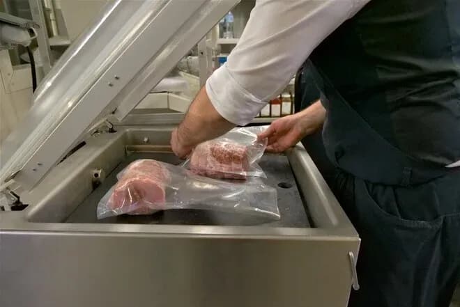 Préparation de morceaux de viande sous vide dans une machine professionnelle en boucherie