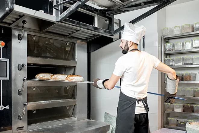 boulanger retirant des miches de pain d'un four professionnel