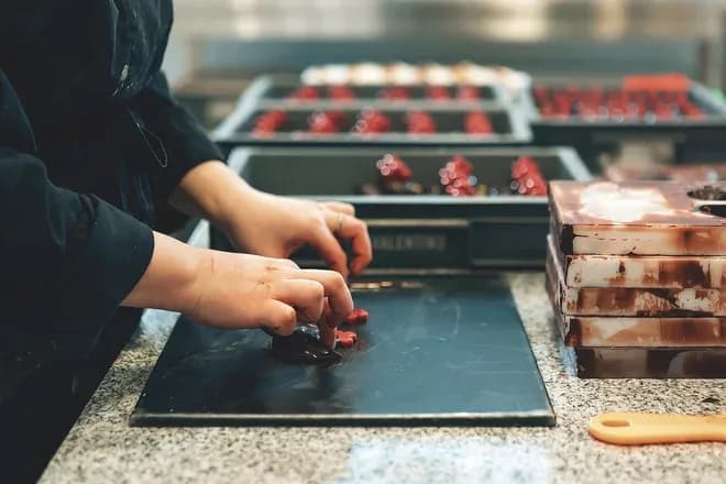 mains d'artisan façonnant des pralines sur plan de travail