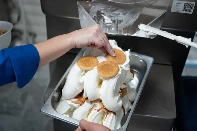 mains décorant une barquette de glace à l'italienne avec biscuits ronds
