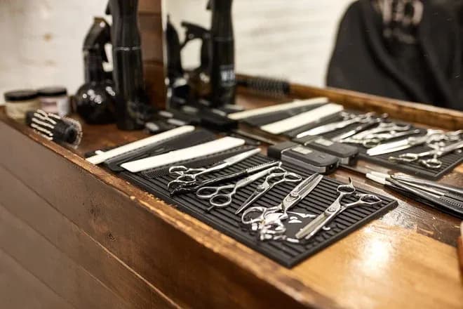 ciseaux, peignes, tondeuse et accessoires coiffure sur comptoir en bois