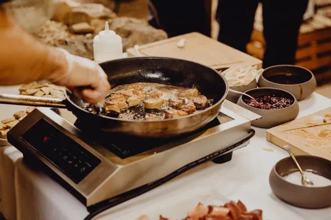 poêle avec des morceaux de viande en train de cuire sur une plaque de cuisson en cuisine