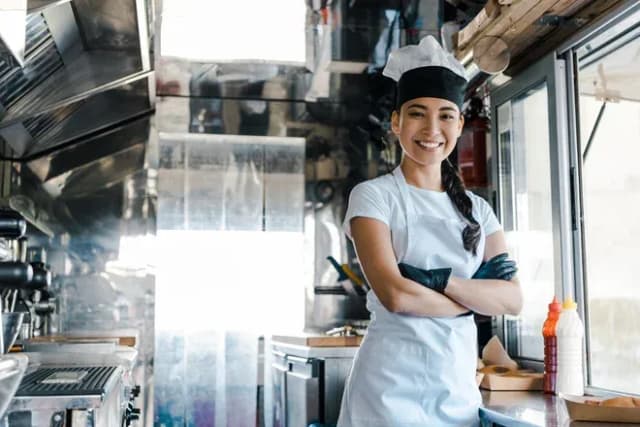 cheffe souriante en tablier et toque à l'intérieur d'un camion-restaurant