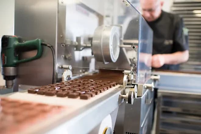 Chocolats en cours de production sur une machine en atelier de chocolaterie