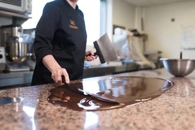 artisan en train de travailler du chocolat sur un plan de travail en marbre