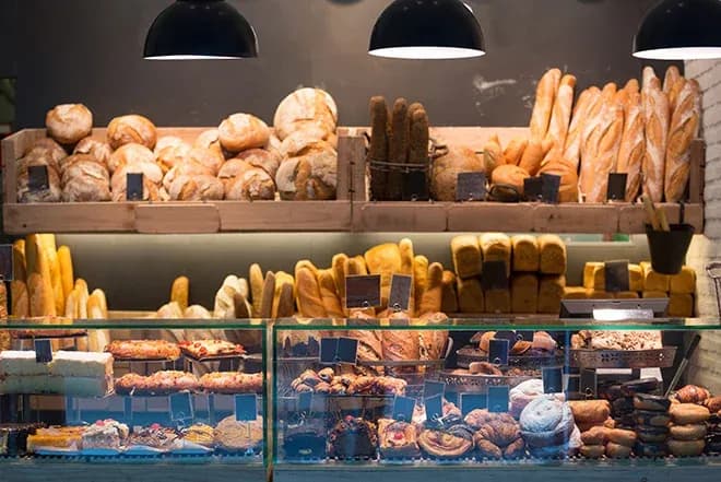 vitrine de boulangerie garnie de baguettes pains et viennoiseries sous lumière chaude