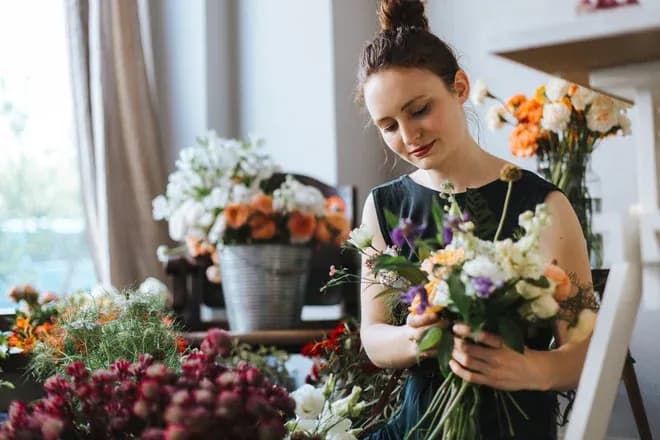 femme souriante tenant un bouquet de fleurs dans un magasin fleuri
