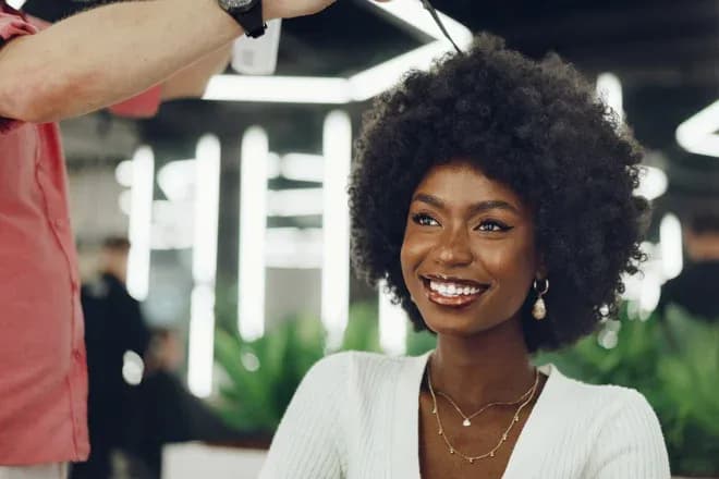 cliente souriante coiffée d'un afro dans un salon