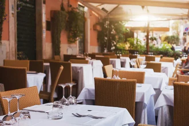 terrasse de restaurant avec tables nappées verres retournés et chaises en résine tressée