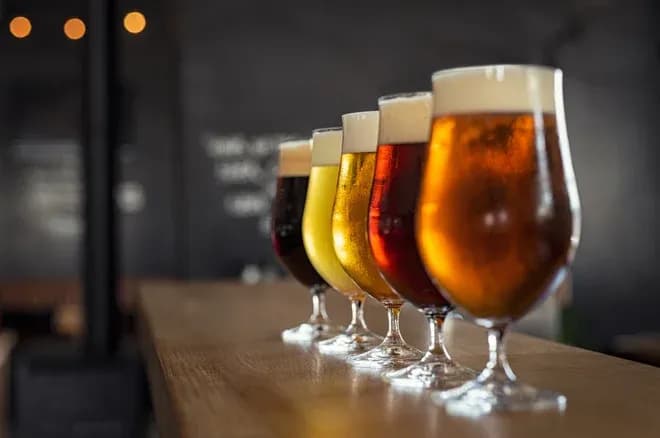 verres de bière variés alignés sur un comptoir en bois