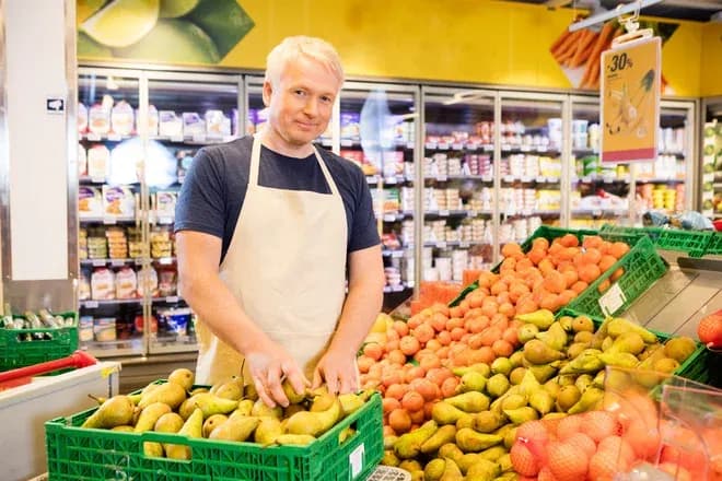 gérant range des poires dans le rayon fruits d'une épicerie
