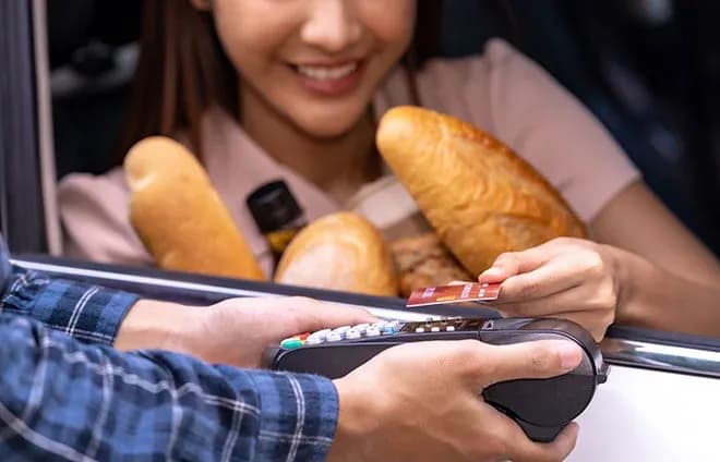 paiement sans contact au drive boulangerie cliente en voiture tenant des baguettes