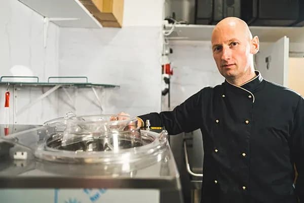 homme en tenue de chef près d'un appareil de pasteurisation en cuisine professionnelle