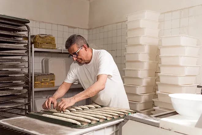 boulanger en train de façonner des baguettes dans une boulangerie artisanale