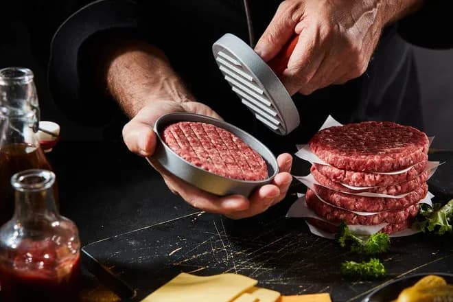 préparation de steaks hachés avec un presse-hamburger sur un plan de travail en cuisine