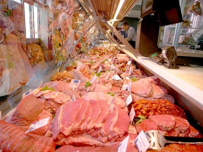 boucherie avec une variété de viandes exposées derrière une vitrine en verre