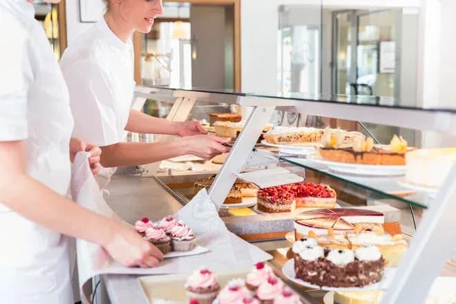 pâtissiers préparant des gâteaux et des cupcakes dans une vitrine de pâtisserie
