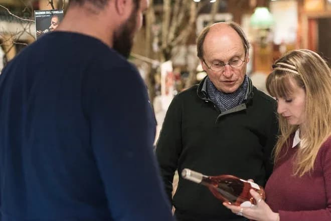 discussion autour d'une bouteille de vin entre trois personnes dans un cadre chaleureux
