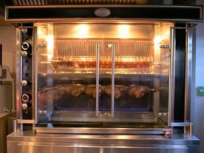 rôtissoire professionnelle en acier inoxydable avec plusieurs morceaux de viande en cuisson