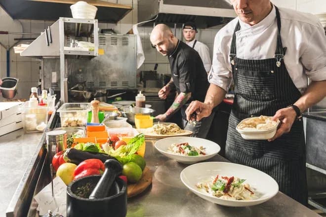 Chefs en cuisine préparant des plats avec des ingrédients frais sur un plan de travail professionnel