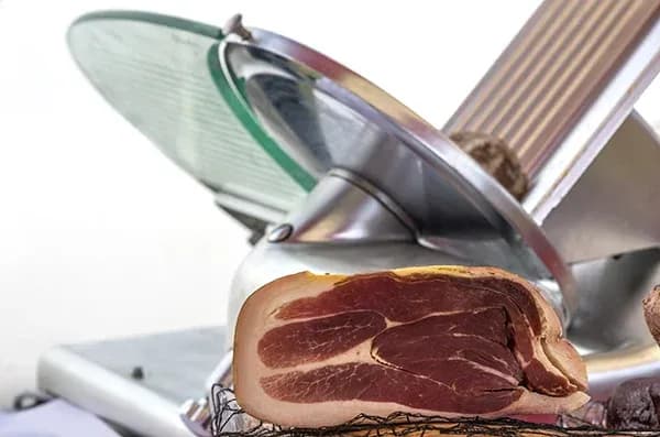 trancheuse en acier inoxydable et morceau de jambon cru