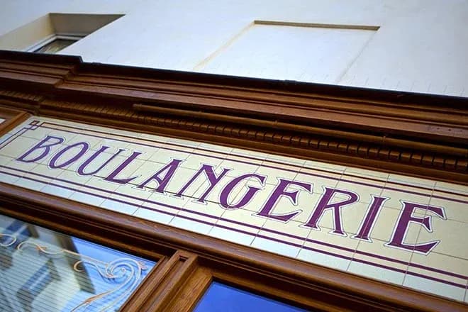 enseigne en faïence d'une boulangerie avec des lettres stylisées en rouge et or