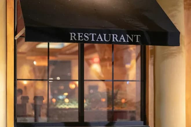 auvent noir portant le mot restaurant au-dessus d'une vitrine éclairée