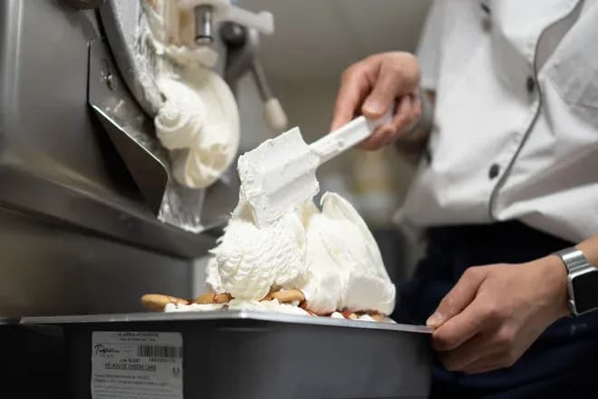 mains d'un employé déposant une glace onctueuse sortie d'une turbine professionnelle