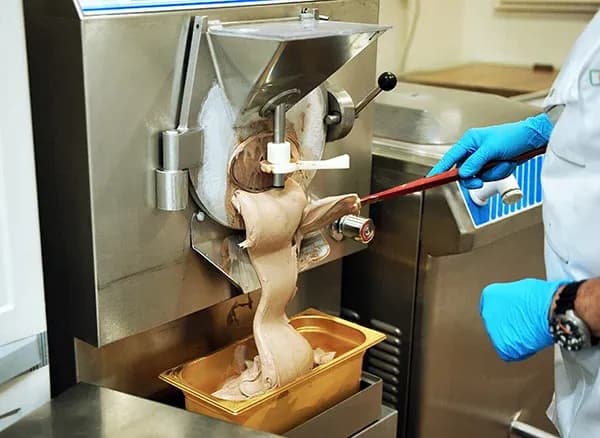machine à glace en fonctionnement avec une personne servant de la glace dans un récipient doré