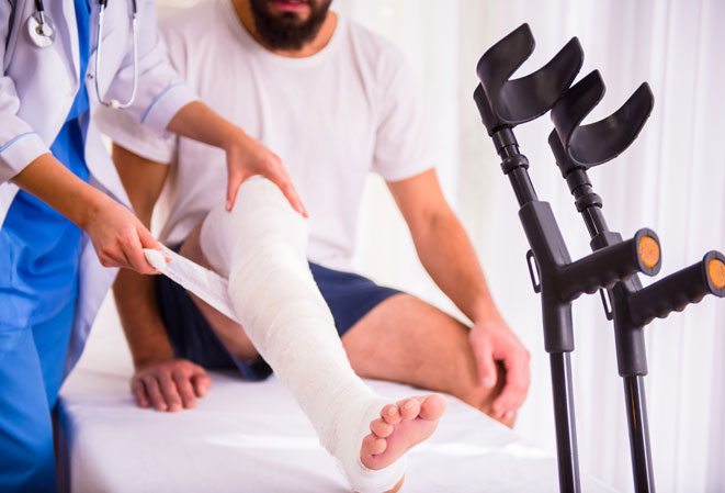 Médecin entrain de plâtrer la jambe fracturée d'un patient