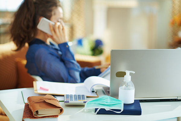 Cheffe d'entreprise s'occupant de ses tâches administratives et parlant au téléphone pendant la crise sanitaire du Covid-19